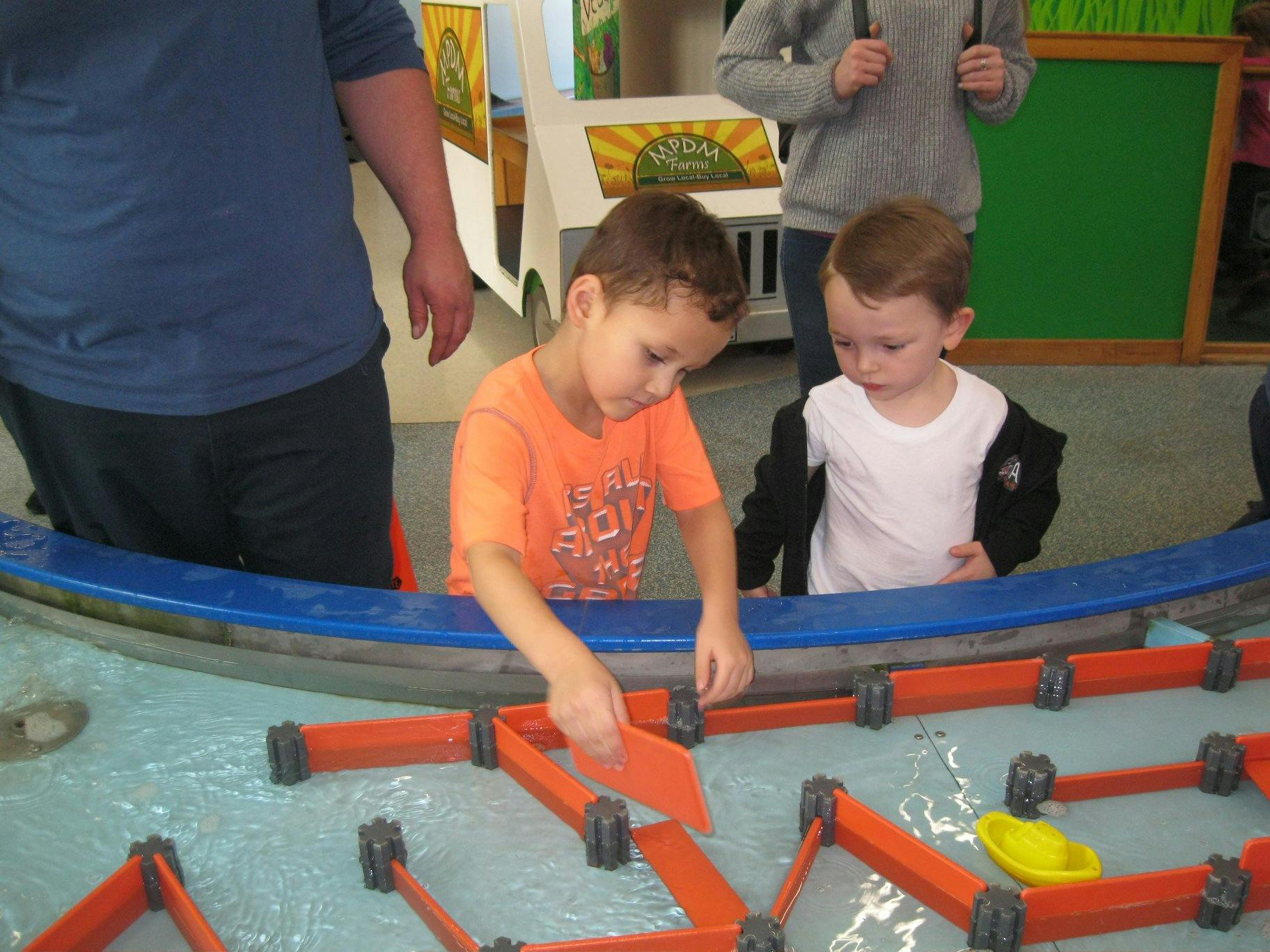 Two children playing with water and orange blocks
