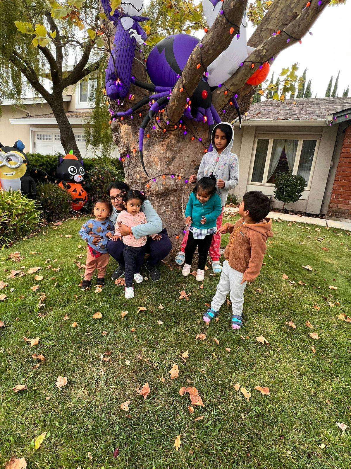 Adult and children gathered around a tree with Halloween decorations