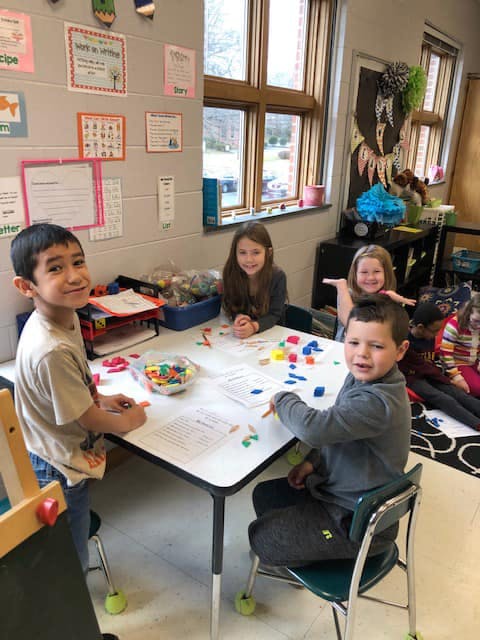Children sitting at a table with colorful learning manipulatives