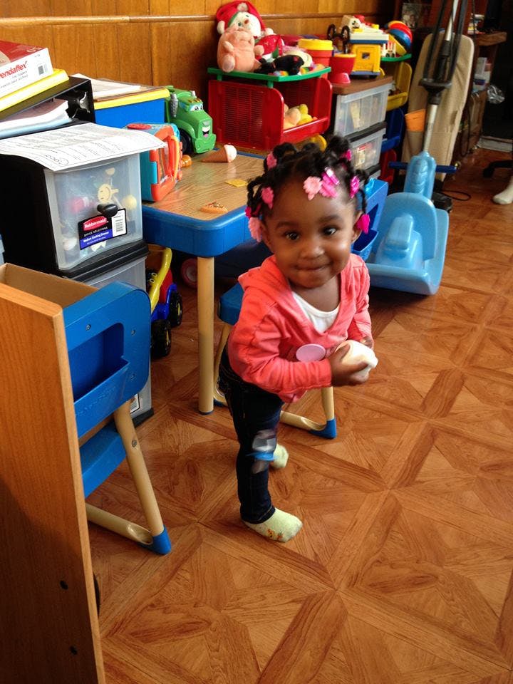 Child standing in a room with toys and a small table