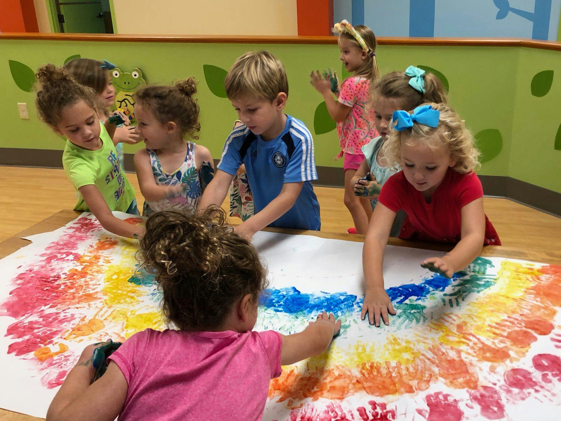Children finger painting on a large sheet of paper