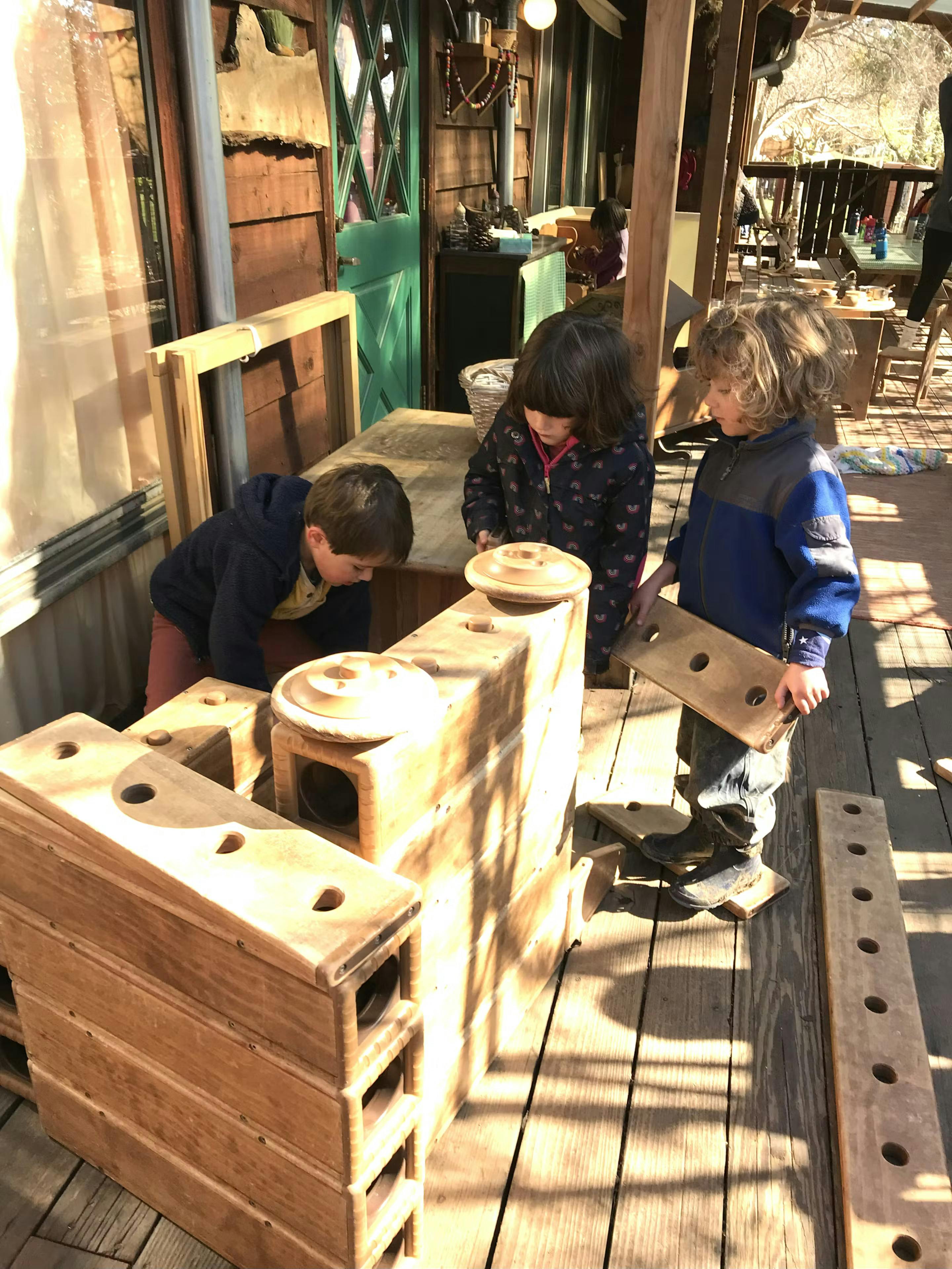 Three children playing with wooden blocks