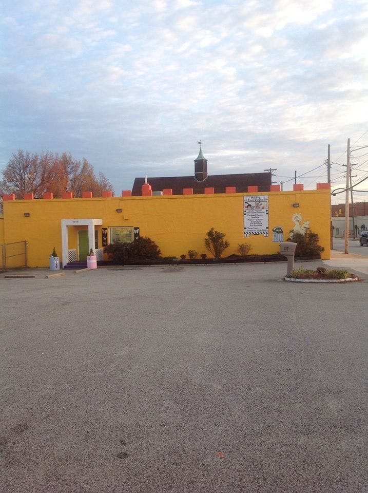 Yellow building with a castle-like facade and a parking lot in front