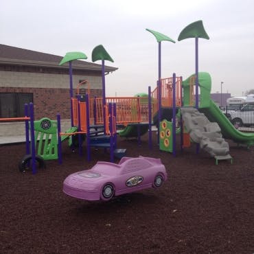 Playground with slides, climbing structures, and a spring rider car
