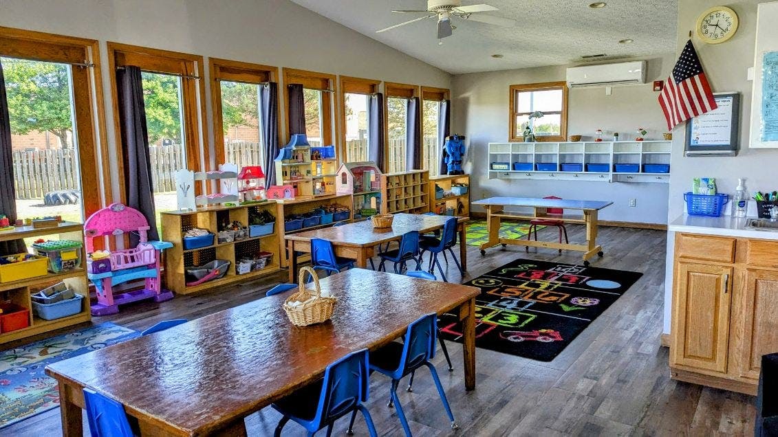 Classroom with small tables and chairs, toys, and an American flag