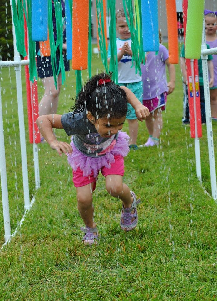 Child running through a water sprinkler