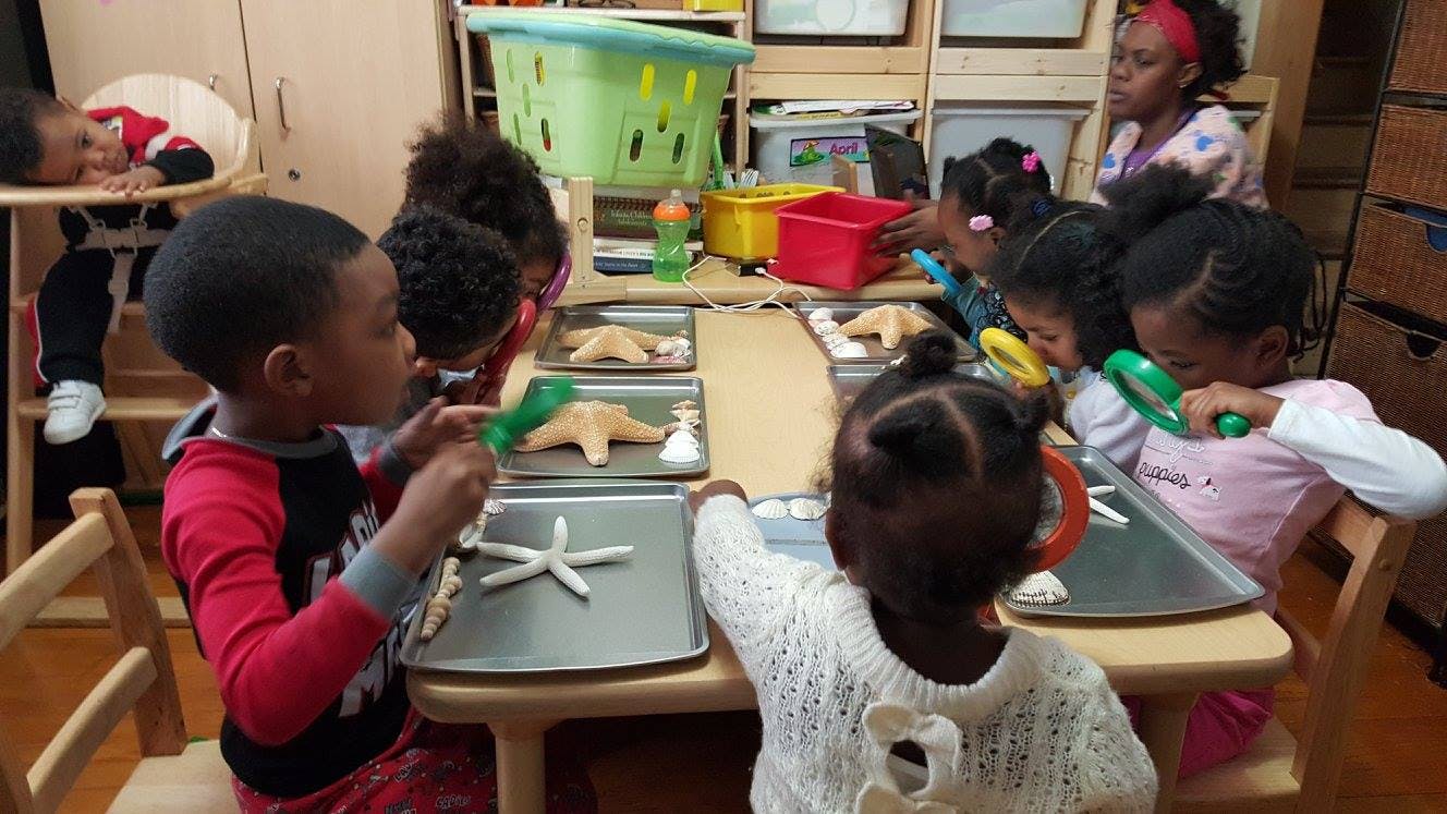 Children at a table playing with starfish and magnifying glasses