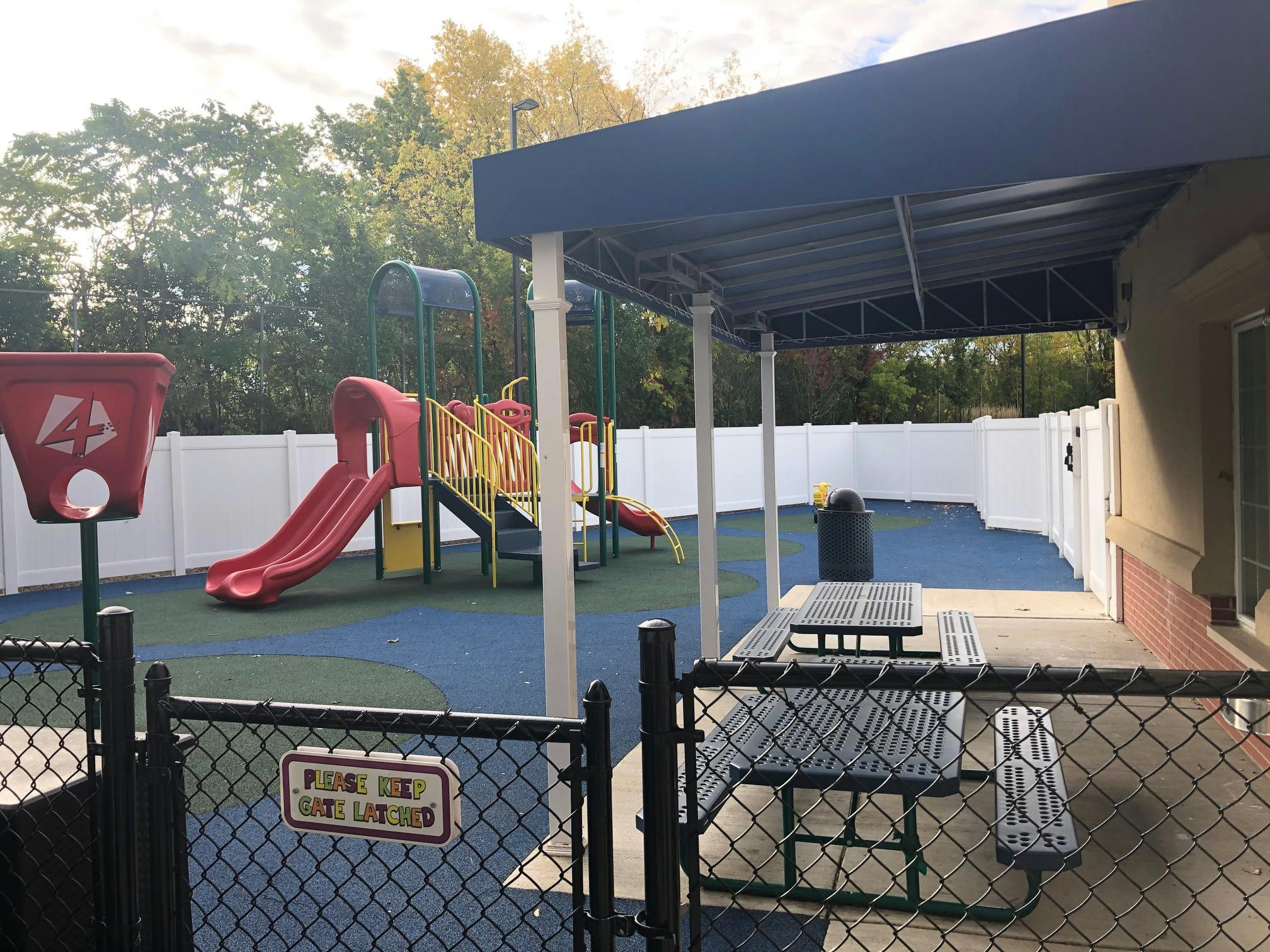 Playground with slides and climbing structure, picnic tables under an awning