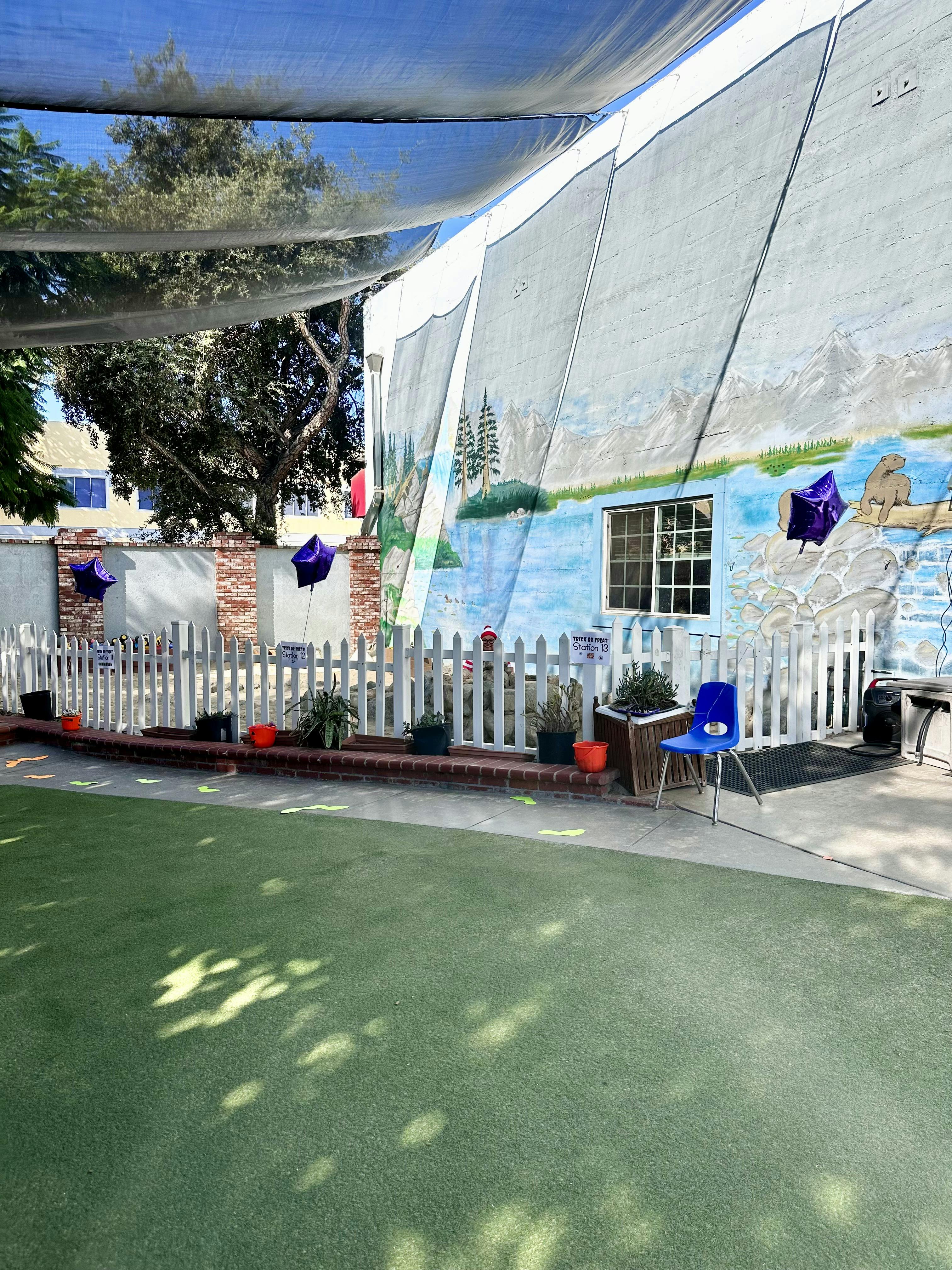 Playground area with a white fence, mural wall, and trick or treat stations