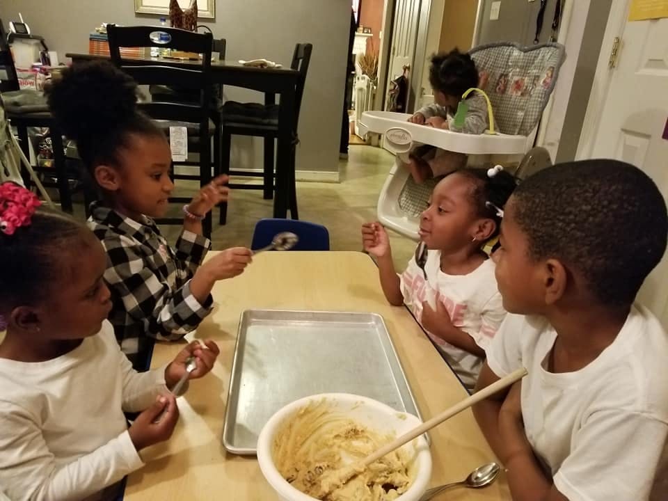 Four children at a table with a bowl of cookie dough