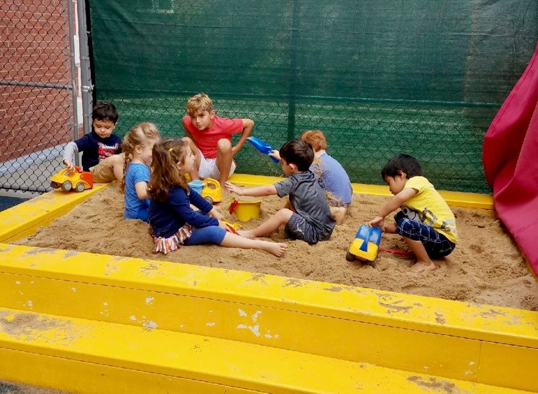 Children playing in a sandbox with toys