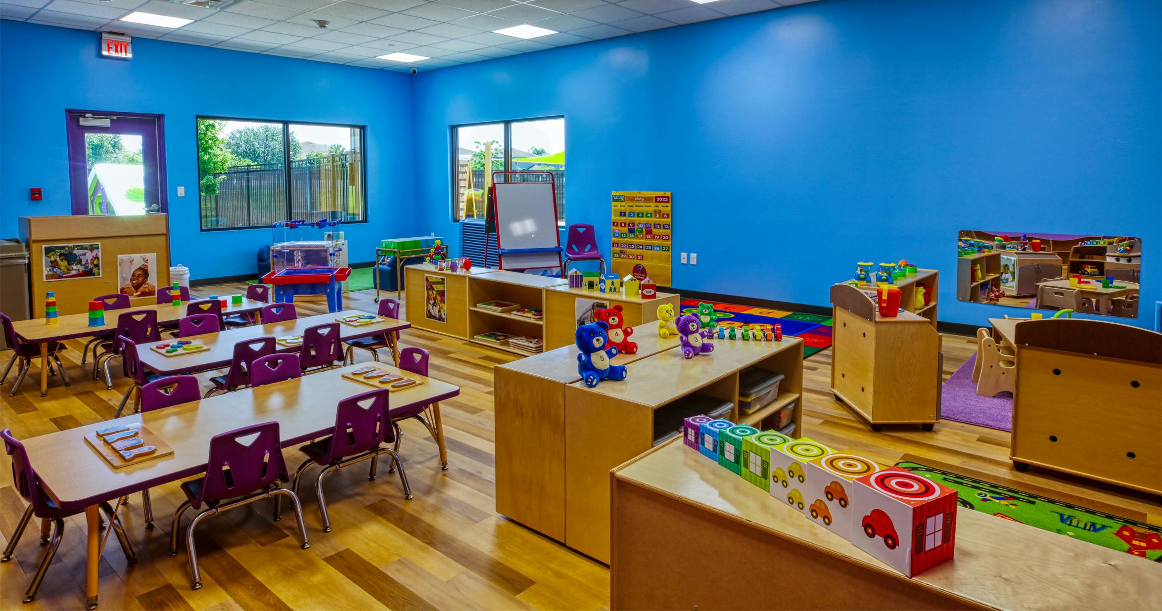 Classroom with small tables, purple chairs, and educational toys