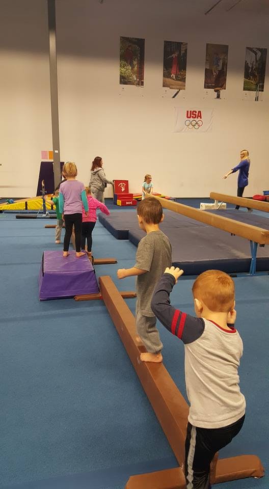 Children walking on balance beams and mats in a gymnastics facility