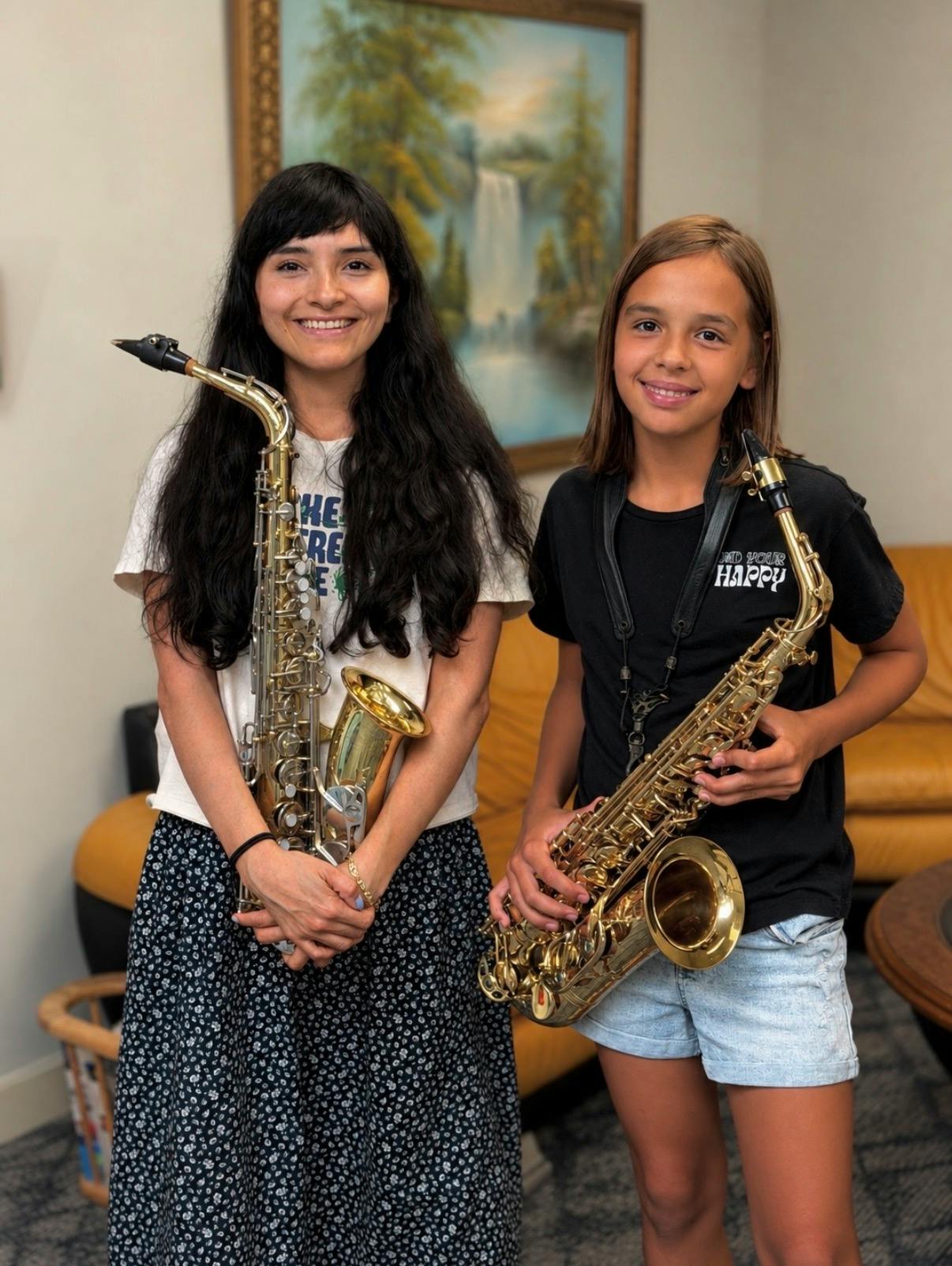 An adult and a child each holding a saxophone