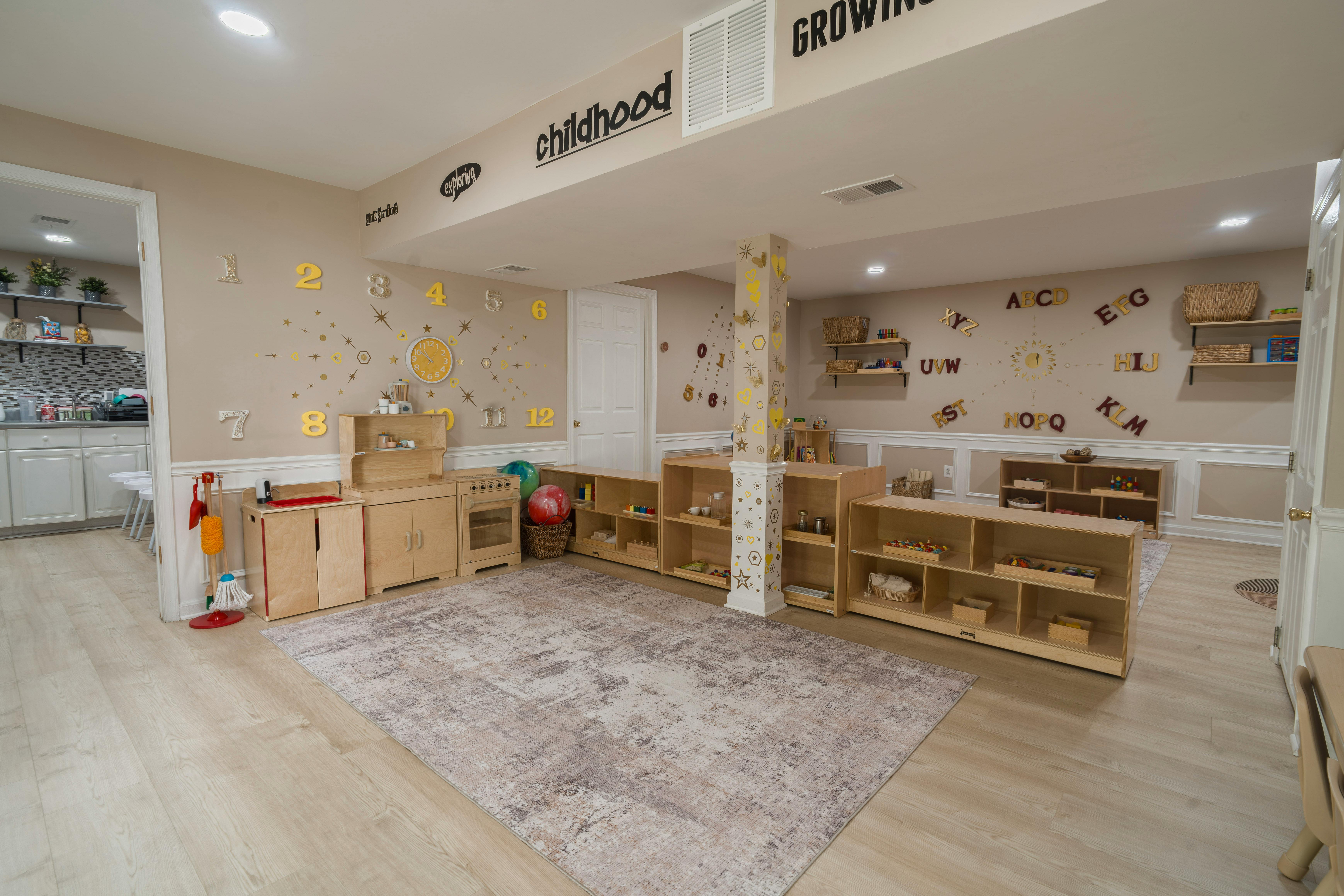 Children's play area with wooden shelves, pretend kitchen, and educational wall decor