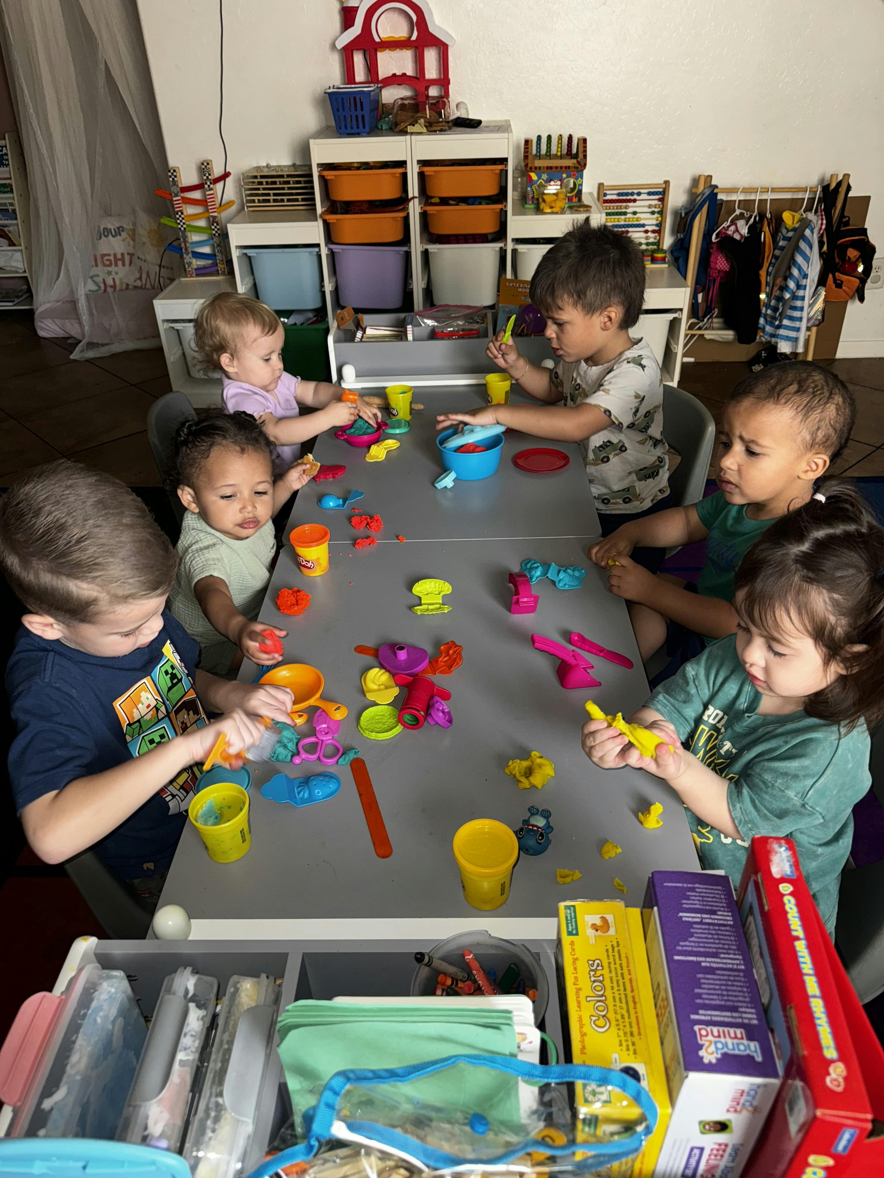 multiple children playing with playdough and molds at a table