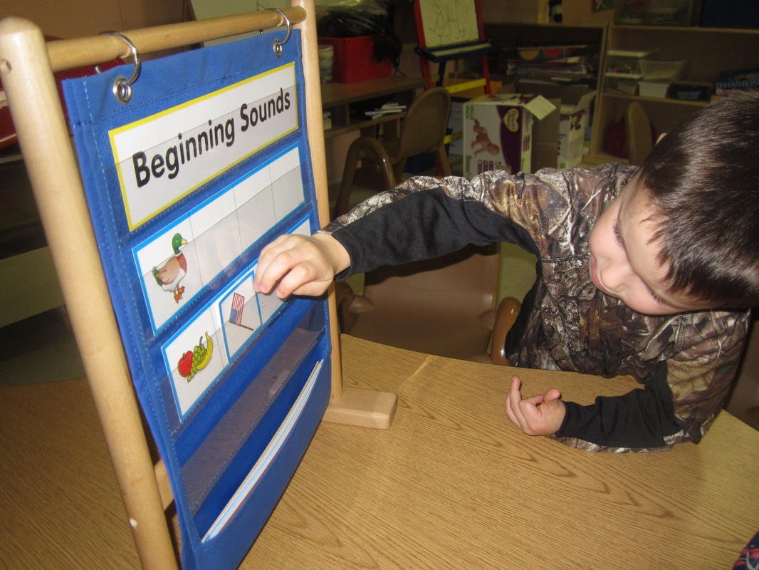 Child interacting with a "Beginning Sounds" learning chart