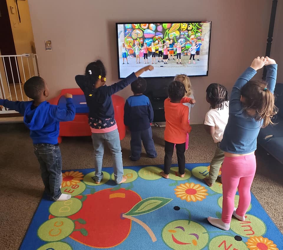 Children dancing in front of a television