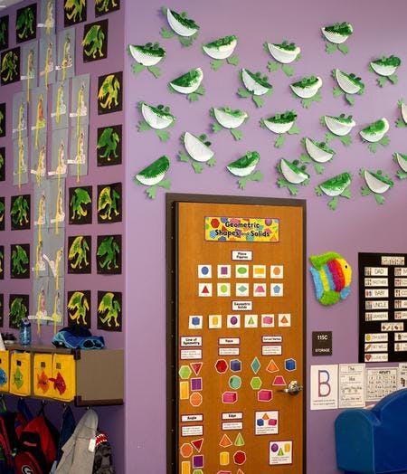 Classroom door with geometric shapes and solids chart, frog cutouts on wall