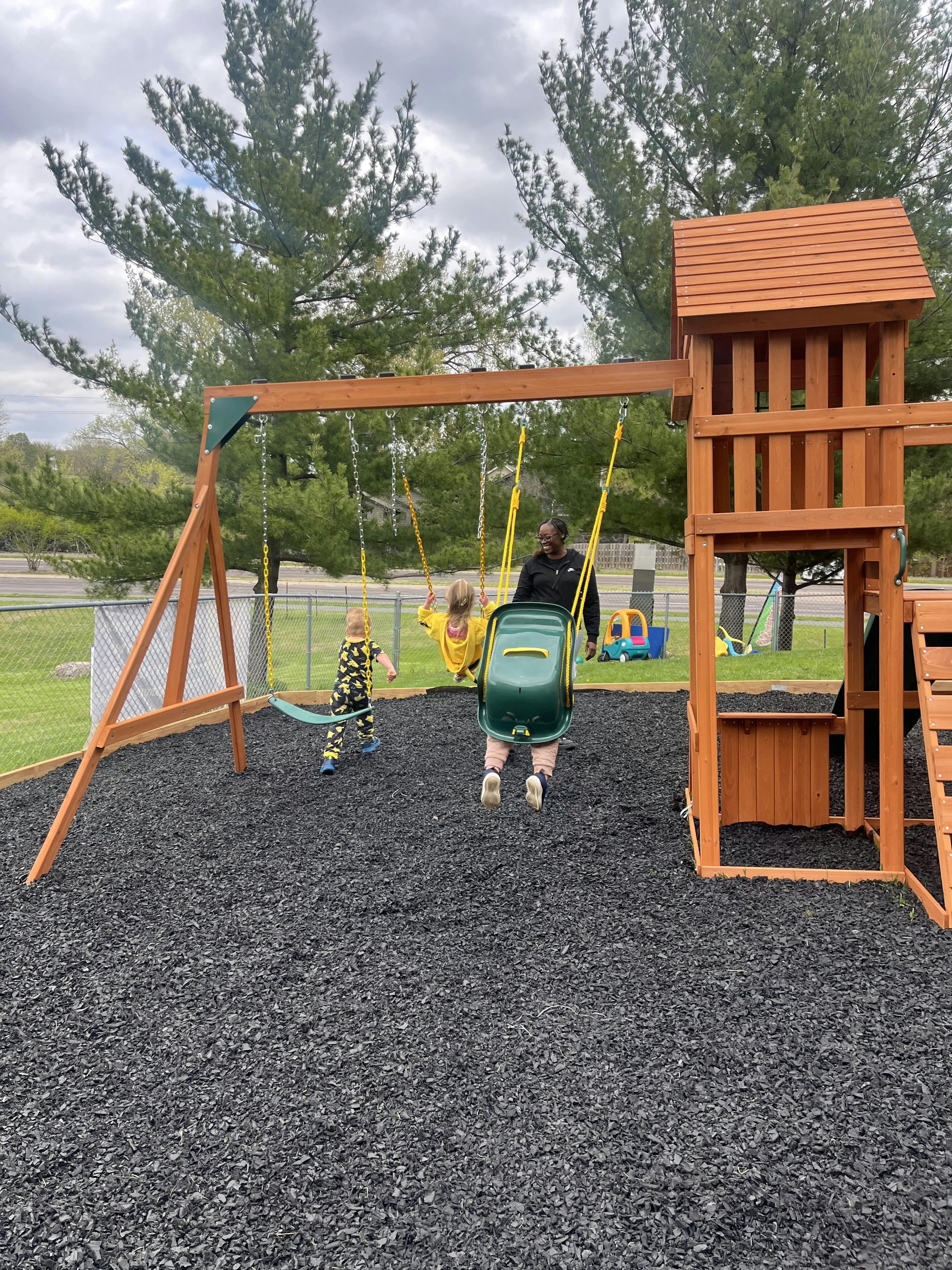 Adult pushing a child on a swing at a playground