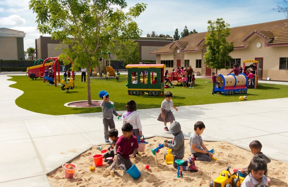 Children playing in a sandbox and on playground equipment outdoors