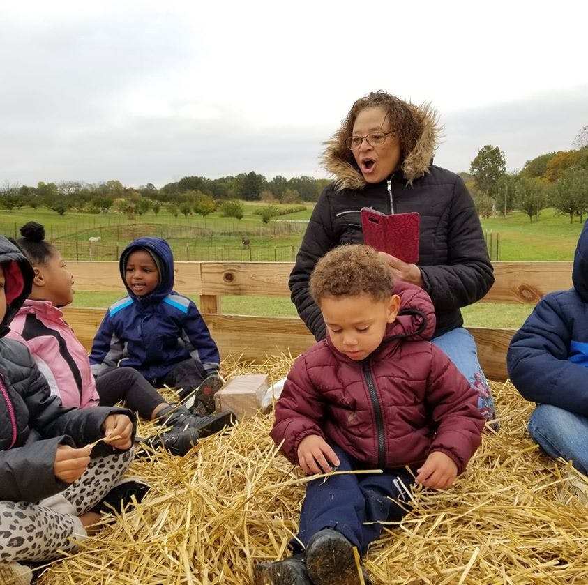 Adult reading to children sitting on hay