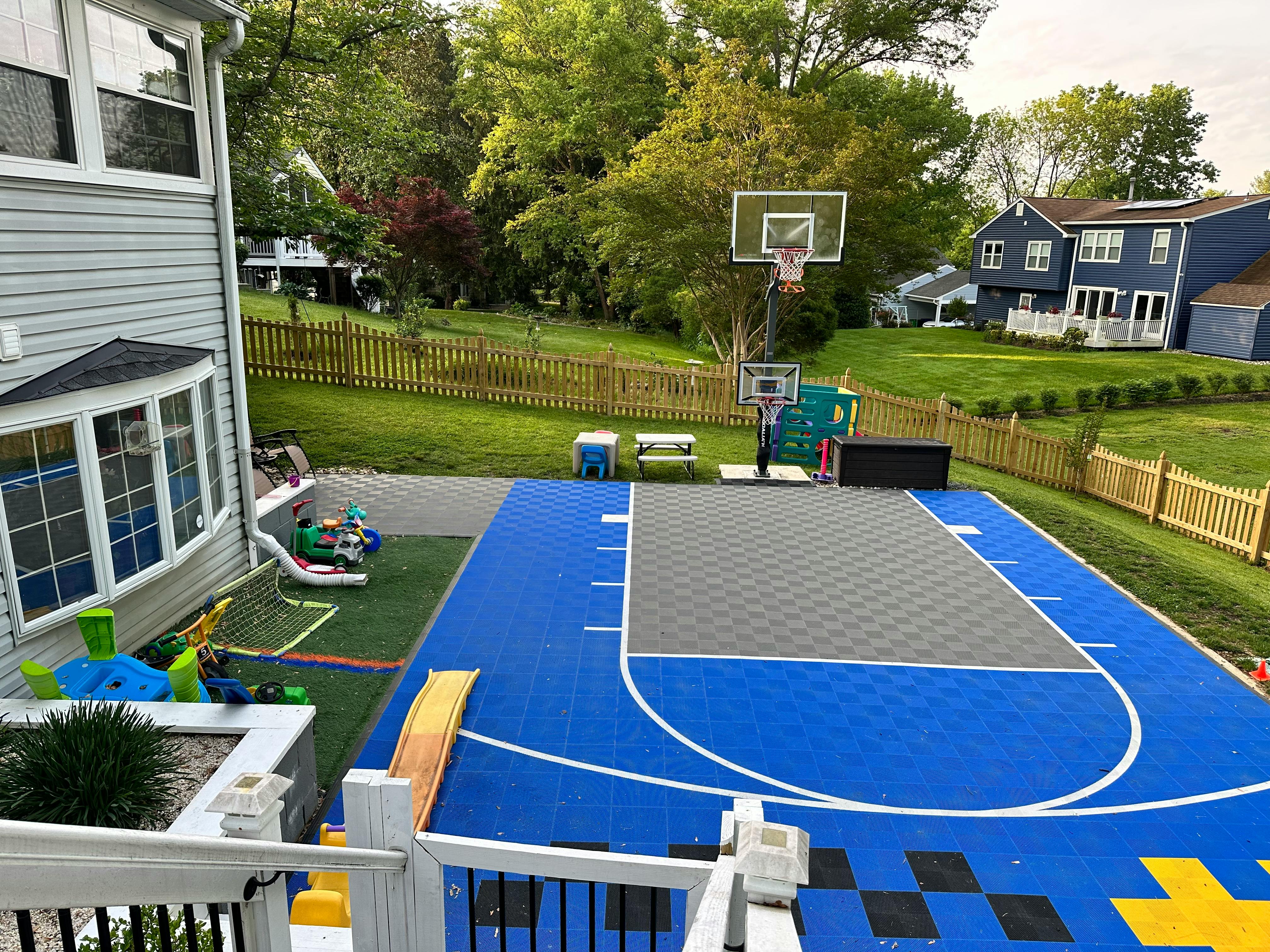 Backyard with a blue and gray basketball court and a house