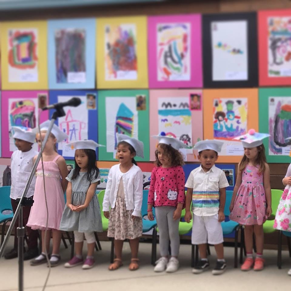 Children in graduation caps standing in front of artwork