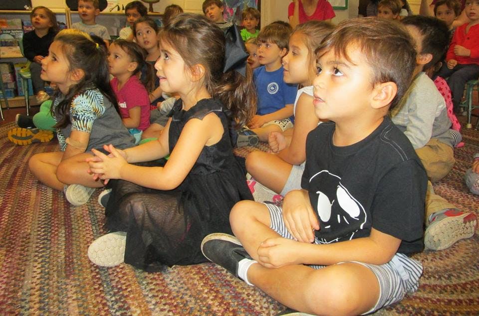 Children sitting on a rug looking forward