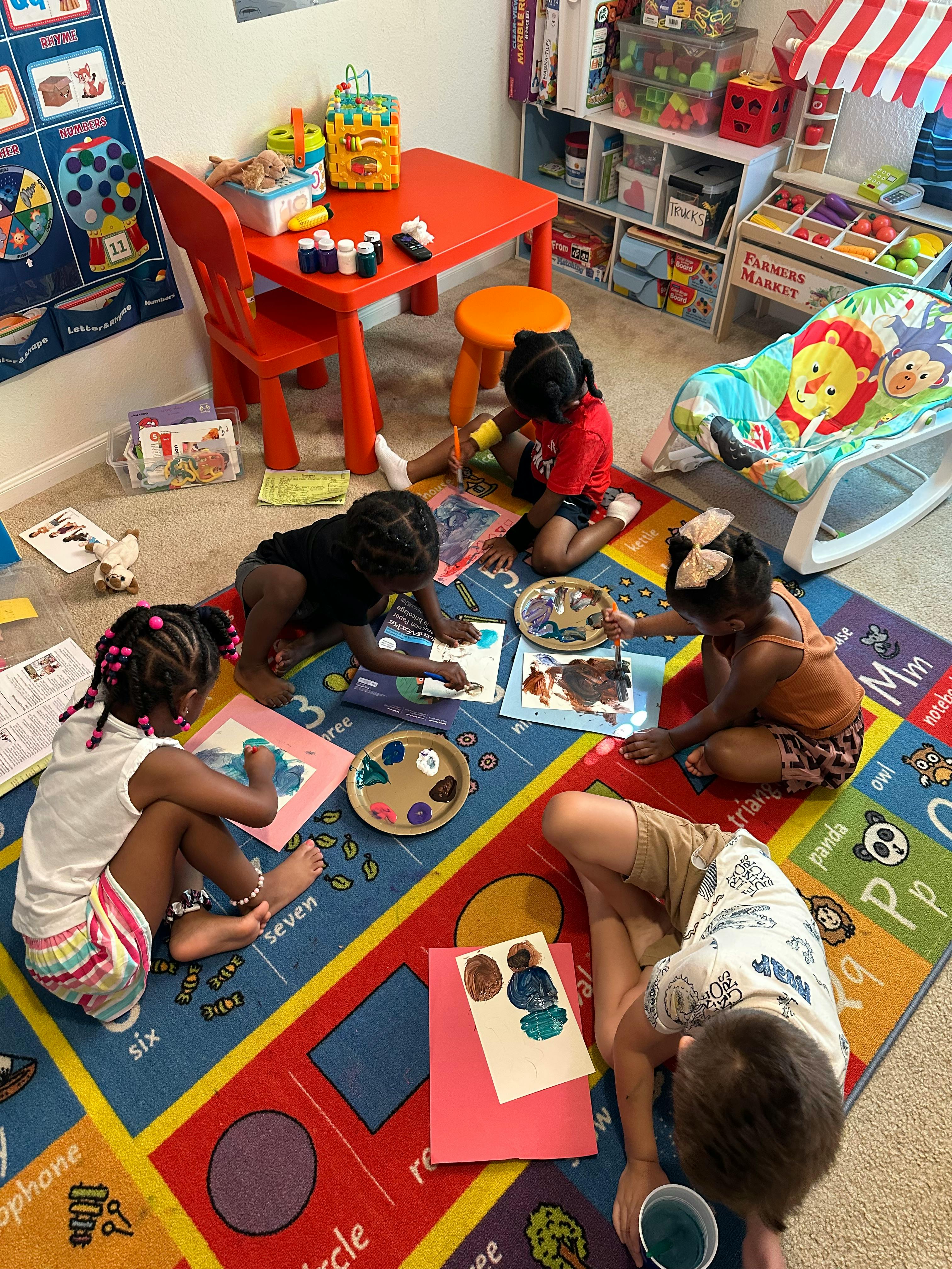 Children painting on a colorful rug