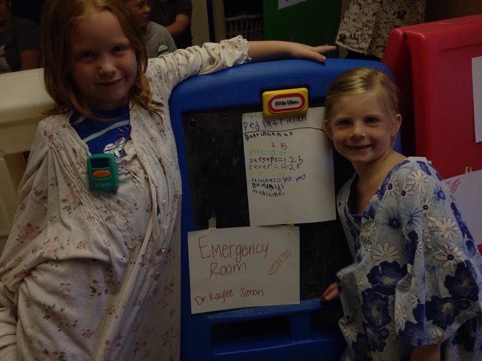 Two children standing next to a blue toy