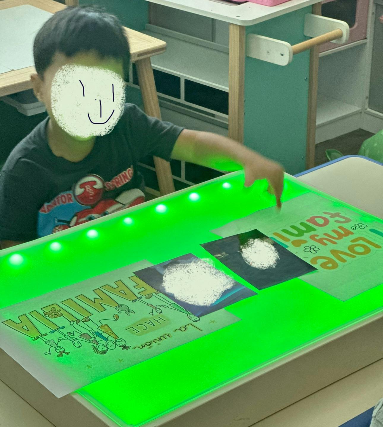 Child interacting with a light table displaying papers