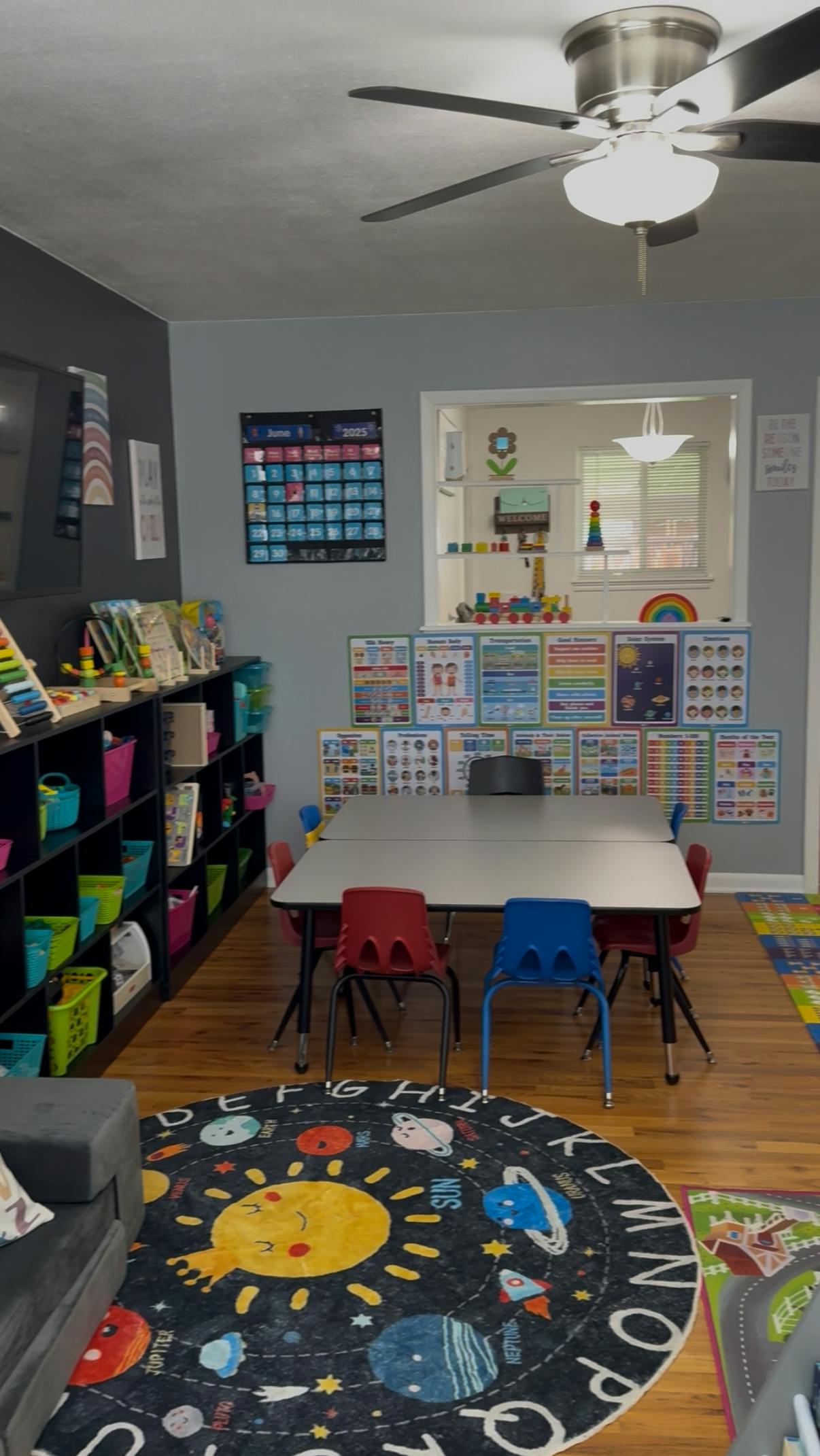 Classroom with a table and chairs, bookshelves, and a space-themed rug