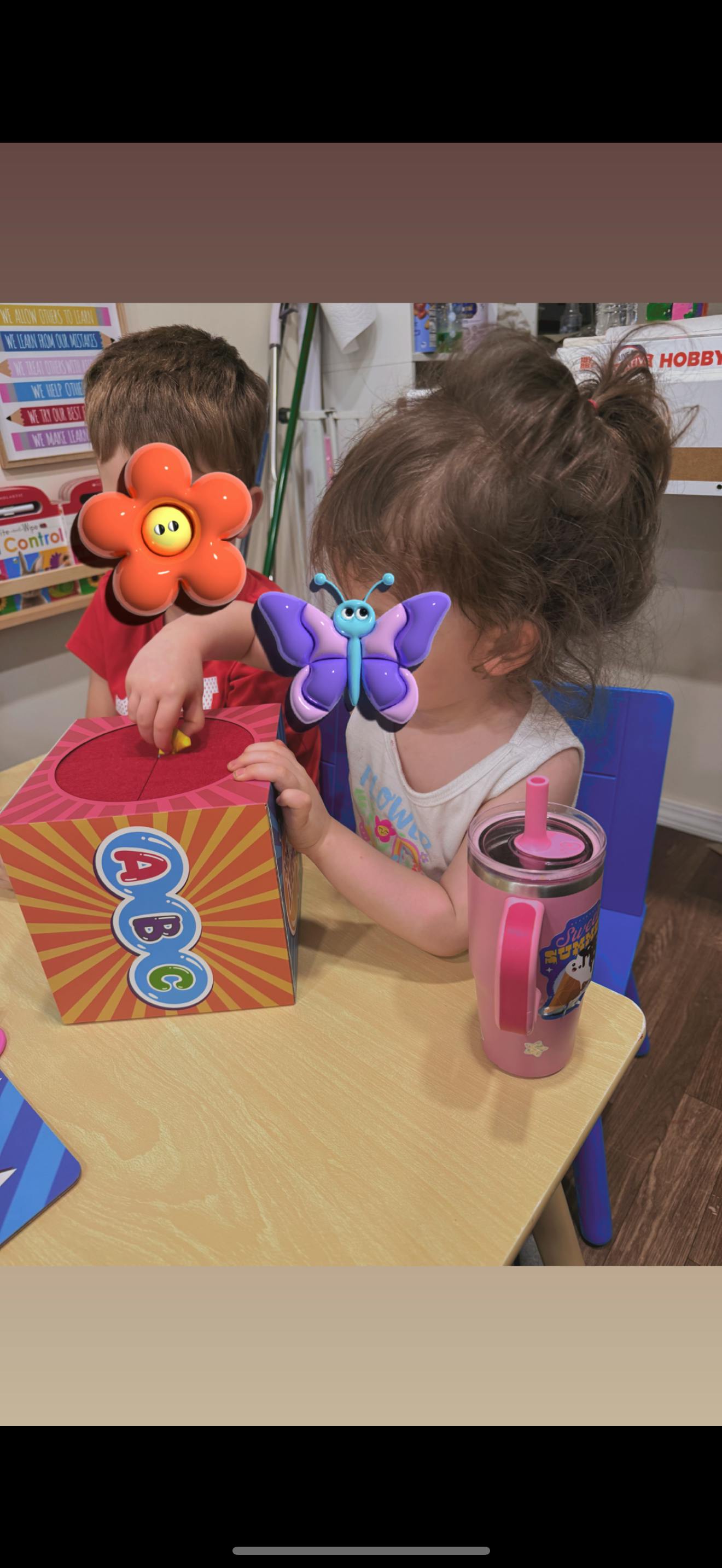 Children playing with a red and orange ABC toy box on a table