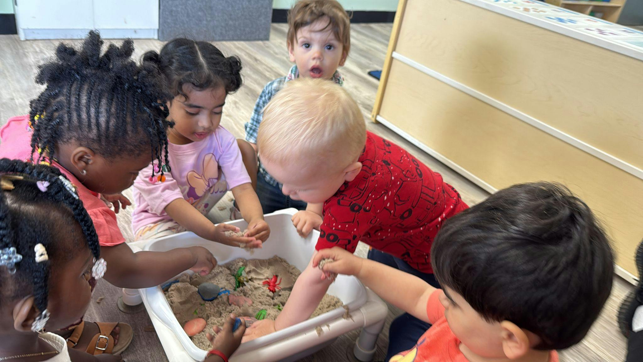 Children playing with sand in a container