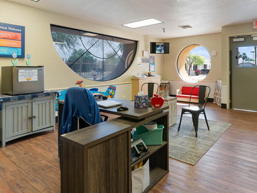 Reception area with a desk, chairs, and two unique windows