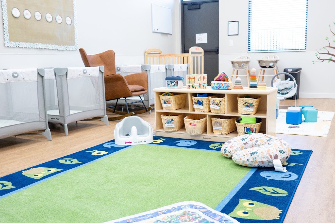 Childcare room with play mats, toy storage shelves, and infant equipment