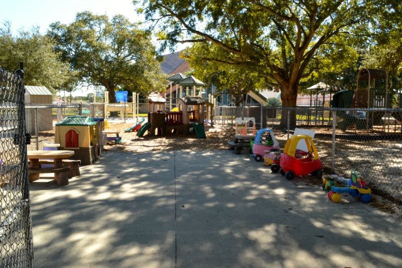 Outdoor playground with play structures, picnic table, and ride-on toys