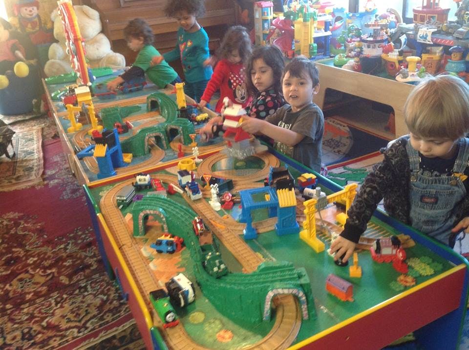 Children playing with a toy train set on a large table