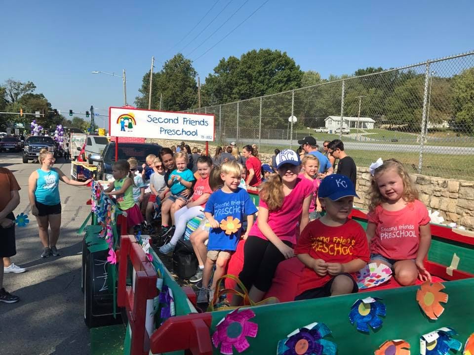 Children and adults on a parade float with a "Second Friends Preschool" sign