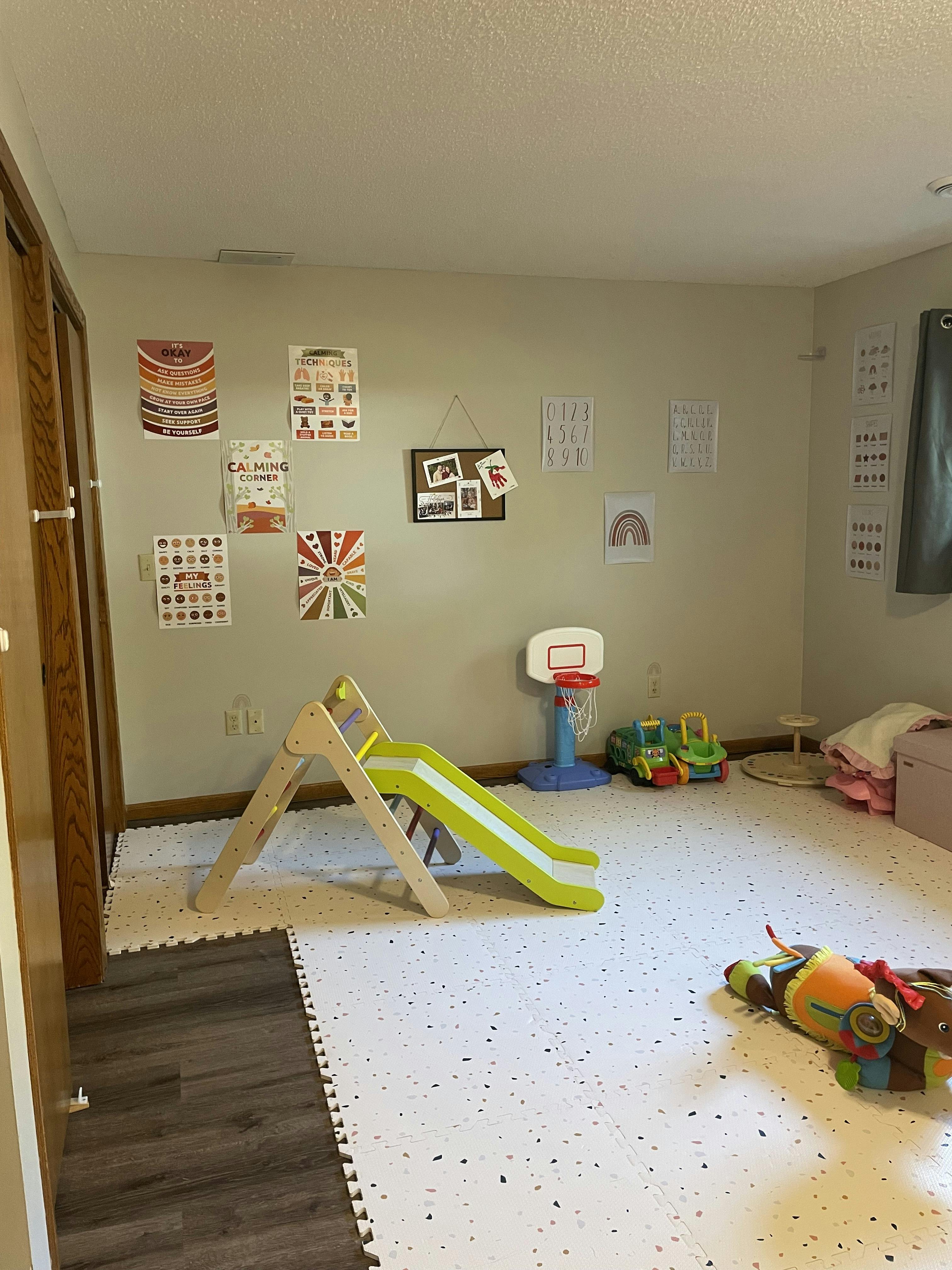 Indoor play area with a slide, basketball hoop, and toys