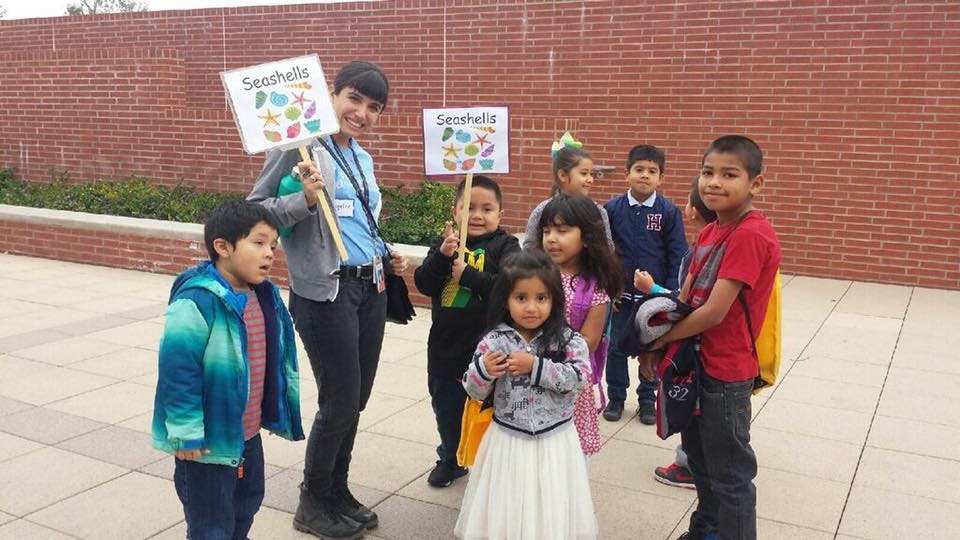 Person holding a "Seashells" sign with children around