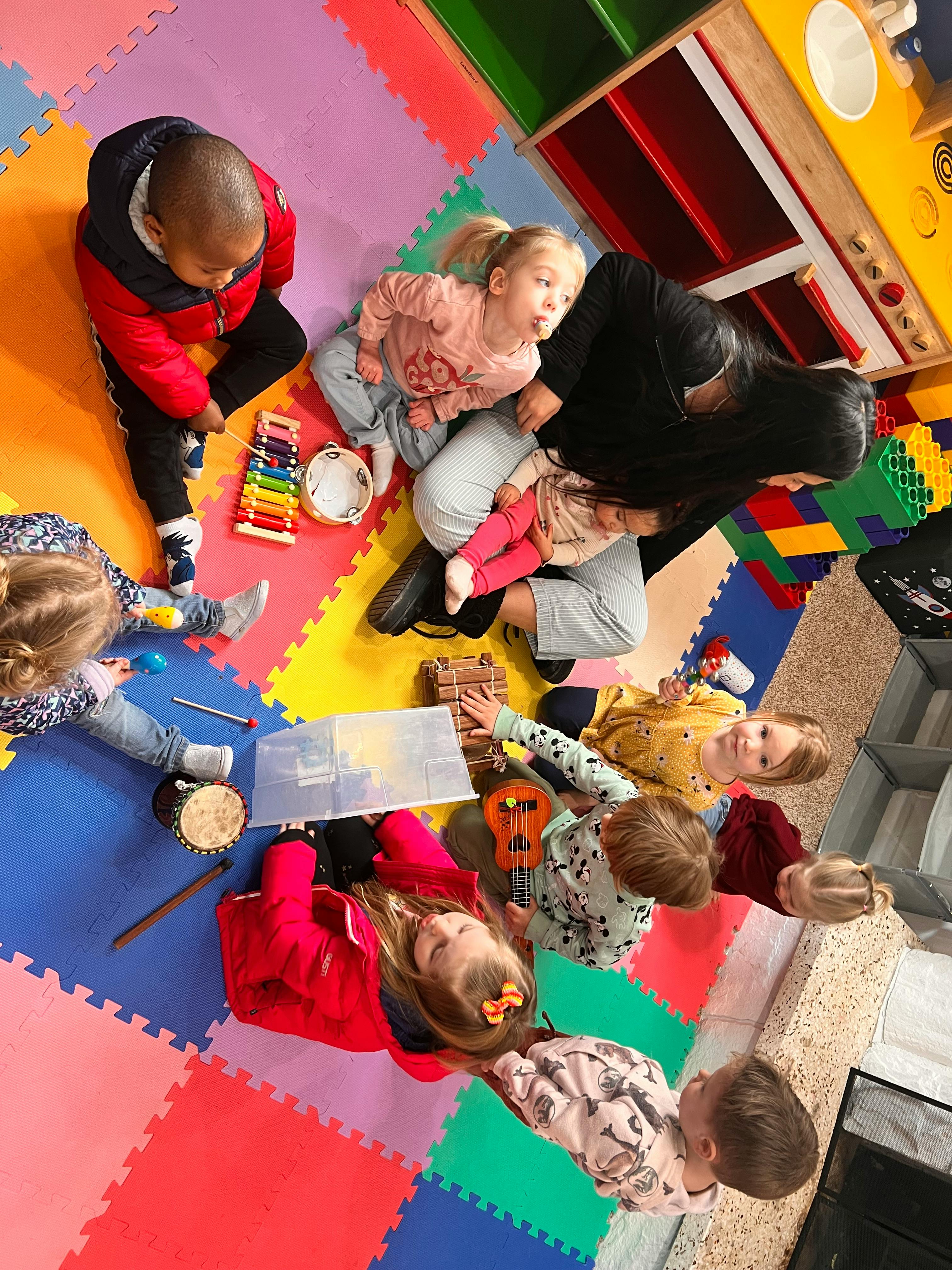 Adult and children playing with musical instruments on a colorful mat