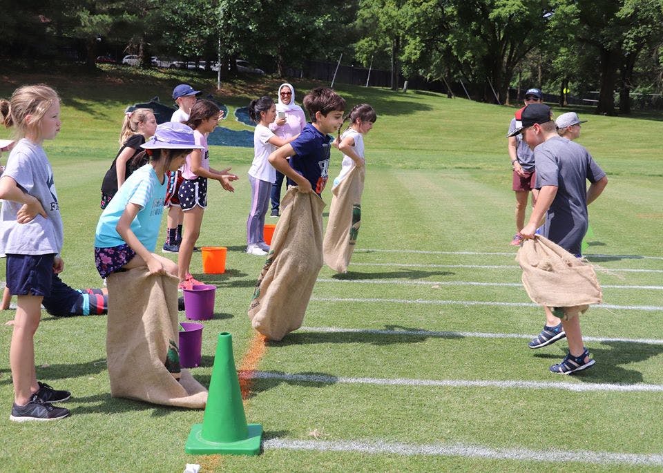 Children and adults participating in a sack race on a grassy field