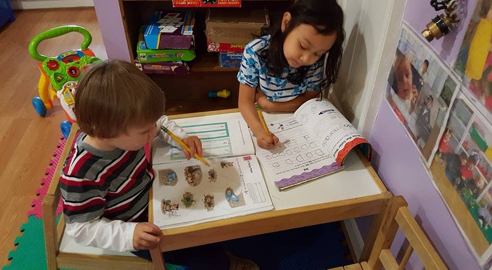 Two children sitting at a table with open books