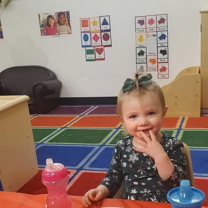 Child with a bow in their hair sitting at a table