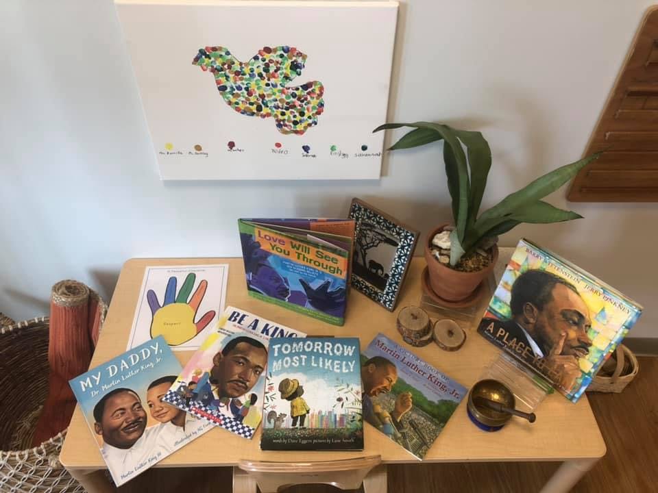Children's books on a table with a plant and artwork