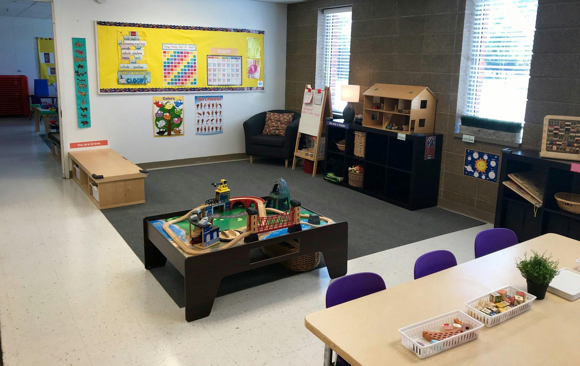 Playroom with a train table, chairs, and educational posters on the wall