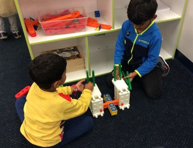 Two children playing with building blocks on the floor