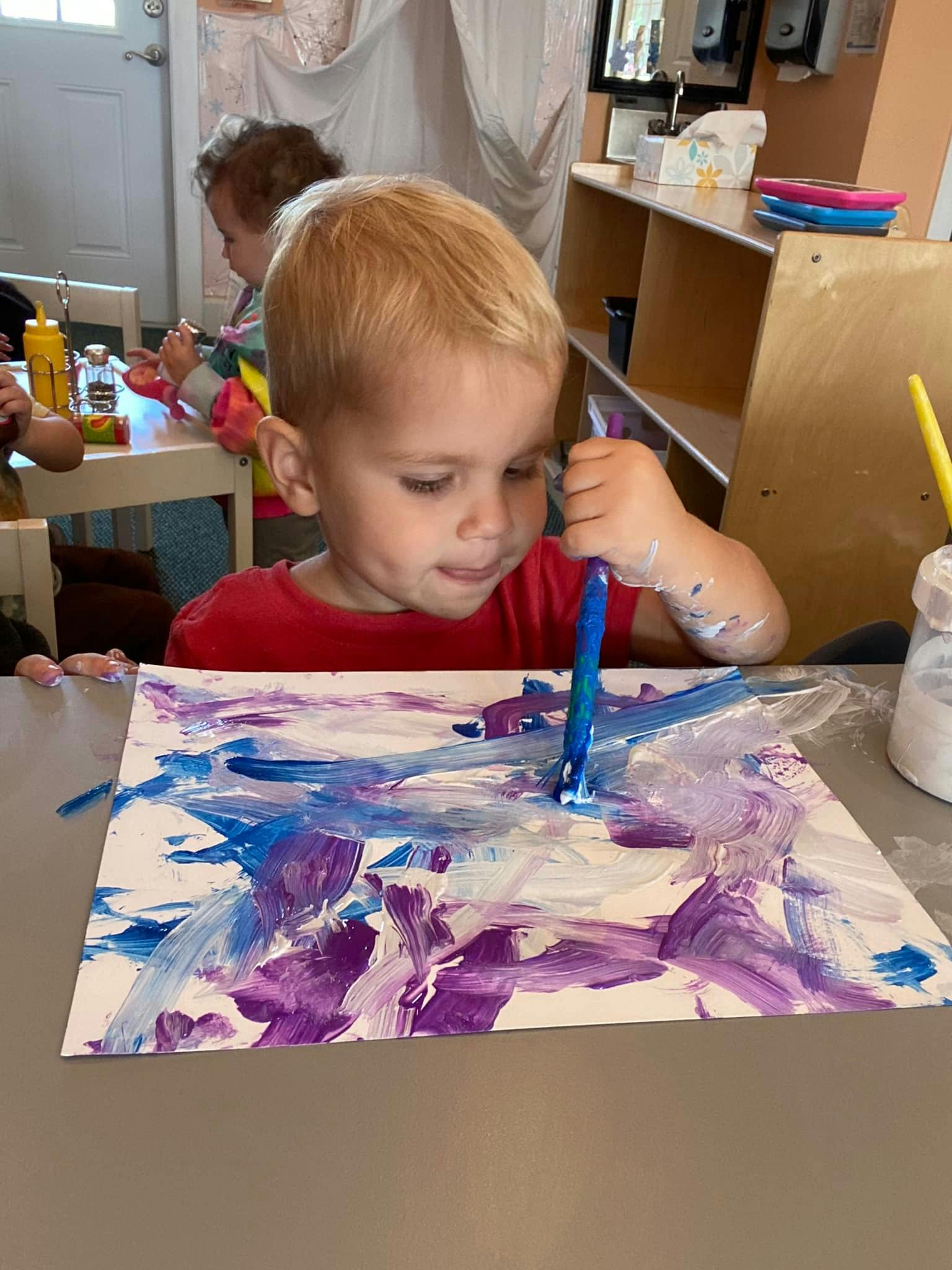 Child painting with a brush on paper